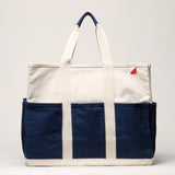 Canvas tote with navy pockets on the outside  and navy cotton grips on the handles