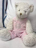 White teddy bear with pink striped overalls and gold monogram.