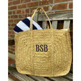 Straw Bag with black monogram holding our beach towel